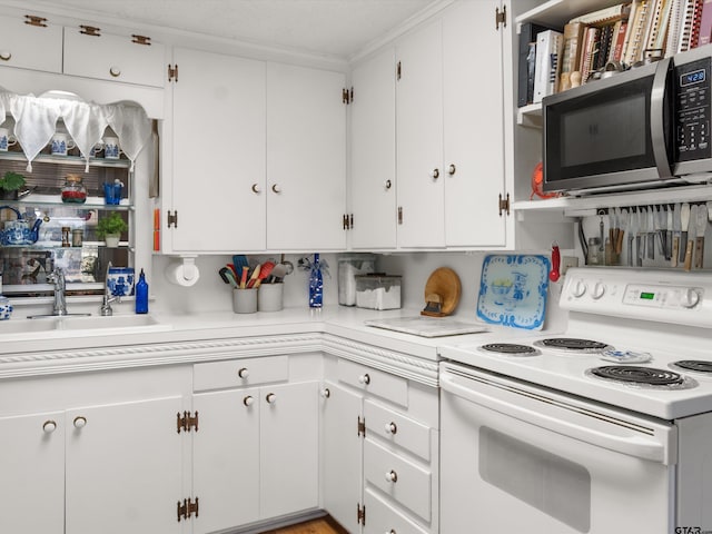 kitchen with electric stove, white cabinetry, and sink