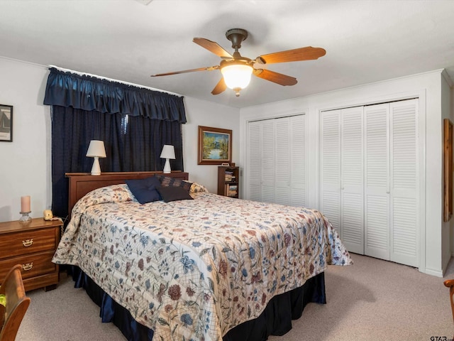 bedroom featuring light carpet, ceiling fan, and two closets