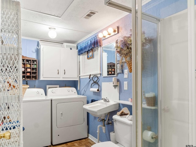 bathroom featuring toilet, parquet flooring, washing machine and clothes dryer, a textured ceiling, and sink