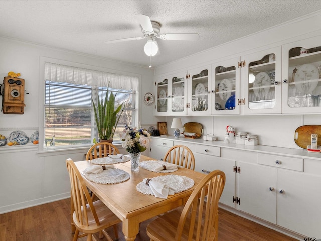 dining area featuring ceiling fan, dark wood-type flooring, a textured ceiling, and crown molding