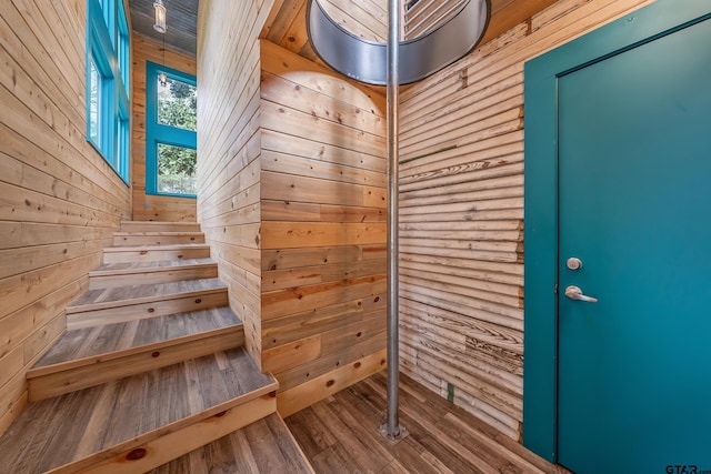 stairs with wood finished floors and wooden walls