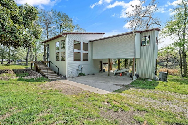 rear view of house featuring stairway, an attached carport, and a lawn
