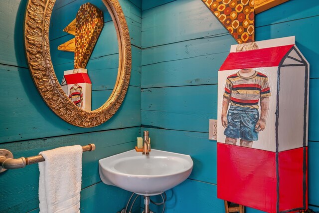 bathroom featuring wood walls and a sink