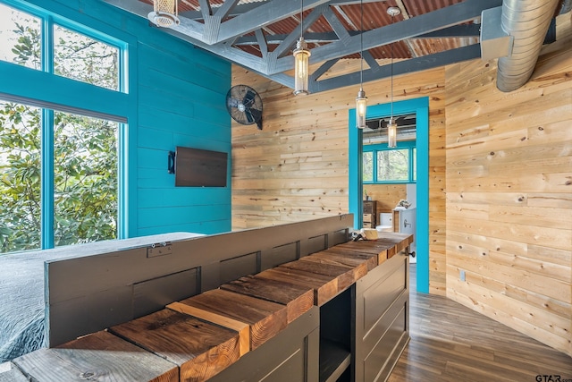 interior space with wood walls, dark wood-type flooring, a towering ceiling, and decorative light fixtures