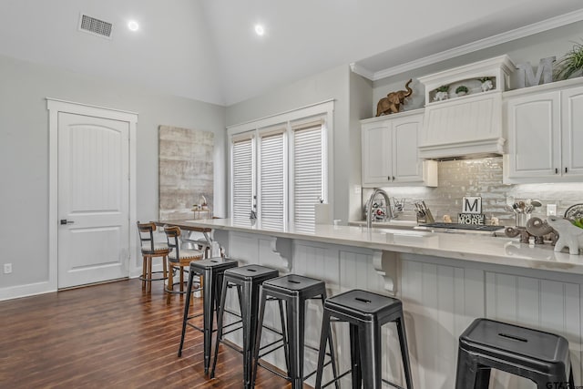 14611 Twin Pines Ln, Lindale, TX 75771 - kitchen featuring white cabinetry, dark wood-style flooring, a breakfast bar, tasteful backsplash, and ornamental molding