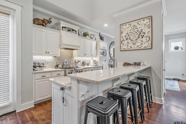 14611 Twin Pines Ln, Lindale, TX 75771 - kitchen with crown molding, dark wood finished floors, a breakfast bar, white cabinets, and backsplash
