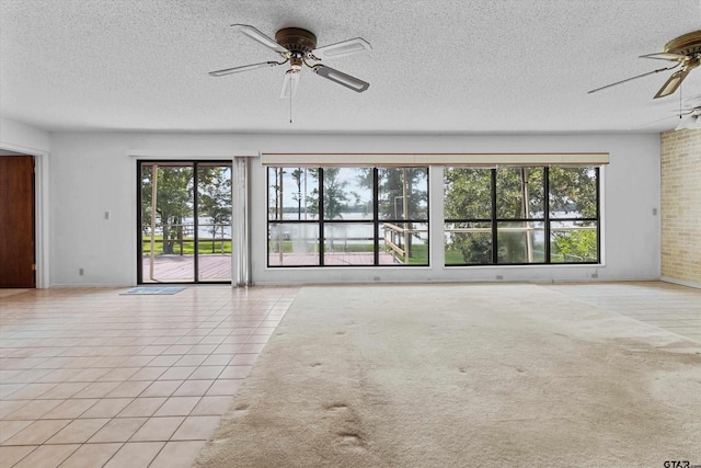 spare room with light tile patterned floors, a textured ceiling, a wealth of natural light, and ceiling fan