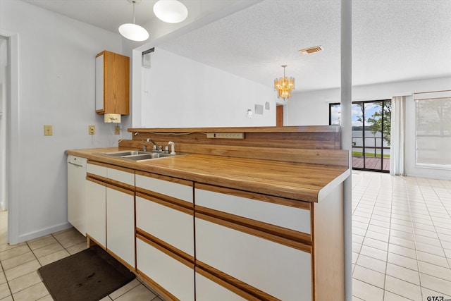 kitchen with a textured ceiling, sink, pendant lighting, light tile patterned floors, and an inviting chandelier