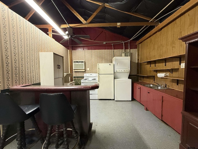 kitchen with stacked washer / drying machine, a wall mounted AC, freestanding refrigerator, a sink, and wallpapered walls