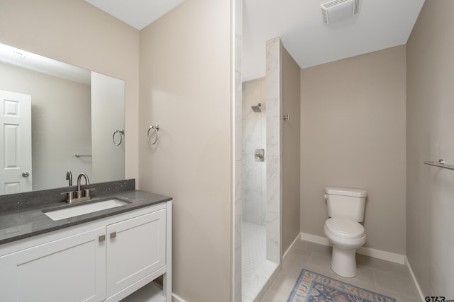 bathroom featuring toilet, a tile shower, vanity, and tile patterned floors