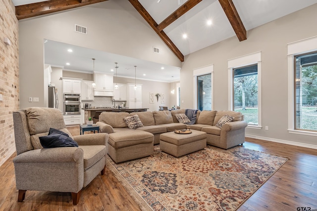 living area with high vaulted ceiling, visible vents, beam ceiling, and wood finished floors