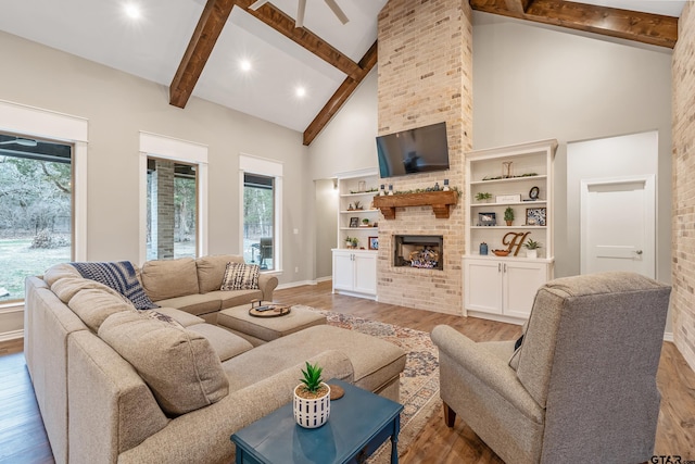 living area with high vaulted ceiling, plenty of natural light, wood finished floors, and a brick fireplace
