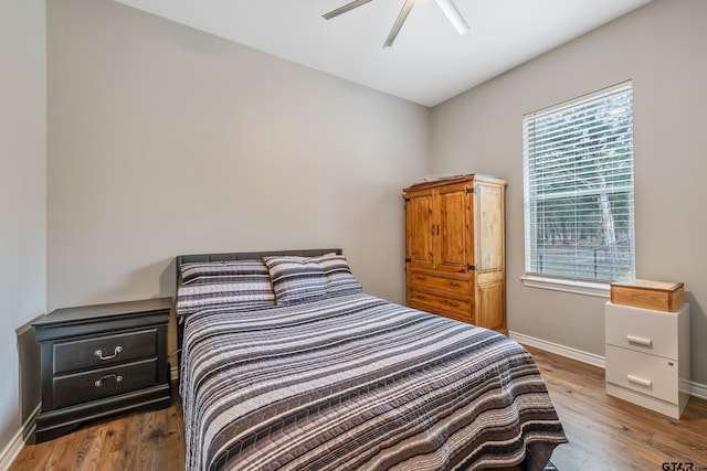 bedroom featuring ceiling fan, multiple windows, dark wood finished floors, and baseboards