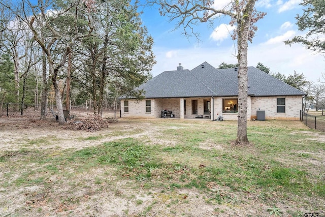 back of property featuring a shingled roof, a chimney, fence, a yard, and central AC