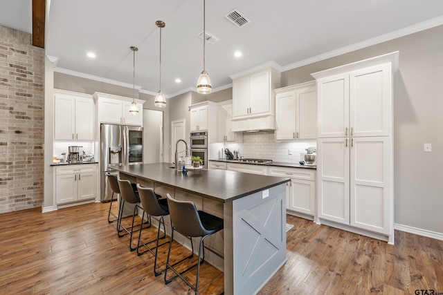 kitchen with visible vents, white cabinets, dark countertops, decorative light fixtures, and stainless steel appliances