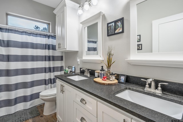 full bath featuring wood finished floors, a sink, toilet, and double vanity
