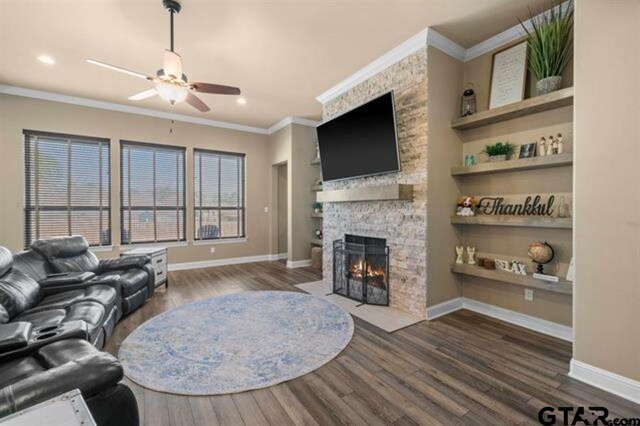 living room with a fireplace, dark hardwood / wood-style floors, ceiling fan, and ornamental molding