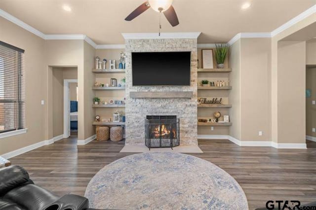 living room with a fireplace, dark hardwood / wood-style floors, ceiling fan, and crown molding