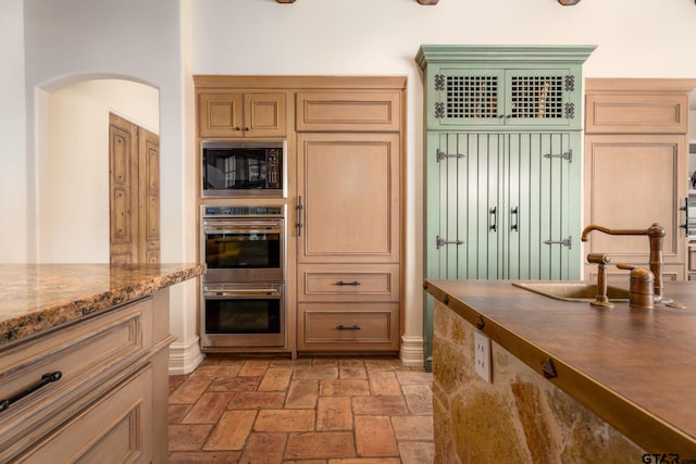 kitchen featuring stone counters, stainless steel double oven, and black microwave