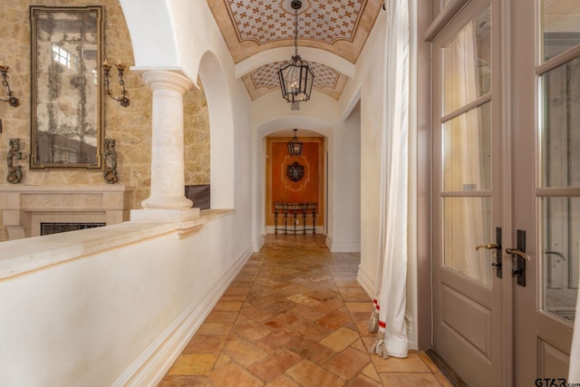 hall with decorative columns, french doors, and lofted ceiling