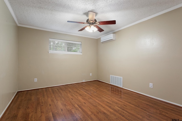spare room with a textured ceiling, a ceiling fan, a wall unit AC, wood finished floors, and visible vents