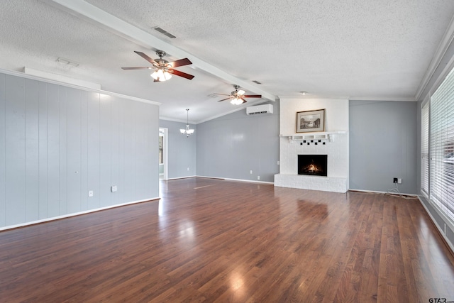 unfurnished living room featuring a fireplace, a wall mounted air conditioner, a textured ceiling, ceiling fan with notable chandelier, and dark wood-type flooring