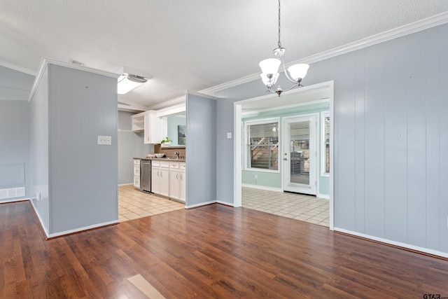 unfurnished dining area with a notable chandelier, ornamental molding, visible vents, and light wood-style floors