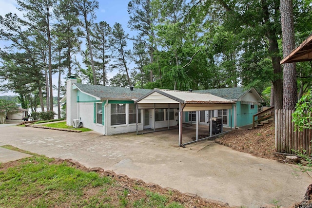 rear view of property featuring driveway, a chimney, and a carport
