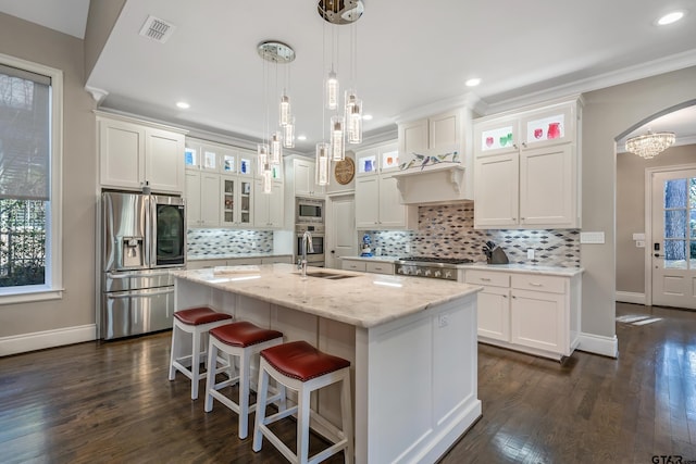 kitchen with visible vents, white cabinets, arched walkways, appliances with stainless steel finishes, and a kitchen island with sink