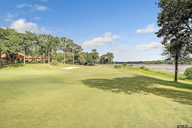 view of home's community with a water view, golf course view, and a yard