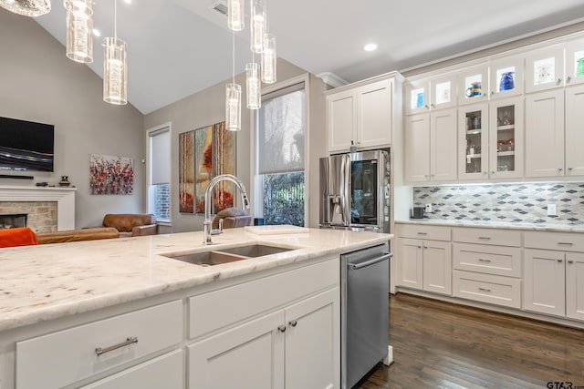 kitchen with pendant lighting, a fireplace, appliances with stainless steel finishes, white cabinetry, and a sink