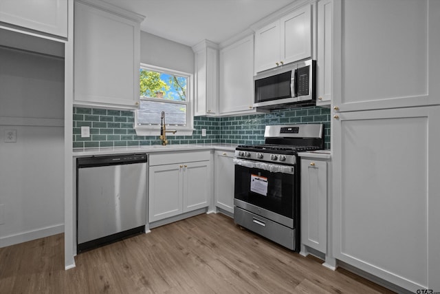 kitchen featuring white cabinetry, sink, stainless steel appliances, and light hardwood / wood-style floors