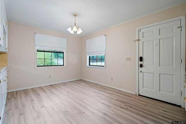 foyer with a chandelier, light wood-type flooring, and crown molding