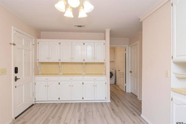 kitchen featuring light hardwood / wood-style flooring, washer / clothes dryer, ornamental molding, and white cabinets