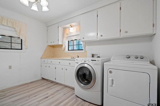 clothes washing area with cabinets, sink, washer and clothes dryer, crown molding, and light hardwood / wood-style flooring