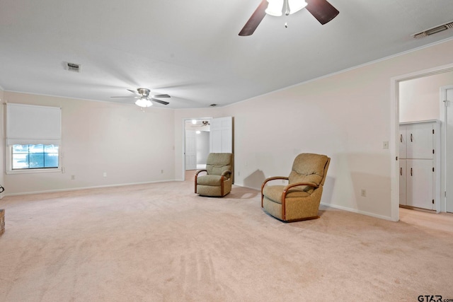 living area with ornamental molding, light colored carpet, and ceiling fan