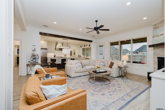 living area featuring visible vents, light wood-style flooring, recessed lighting, ceiling fan, and crown molding