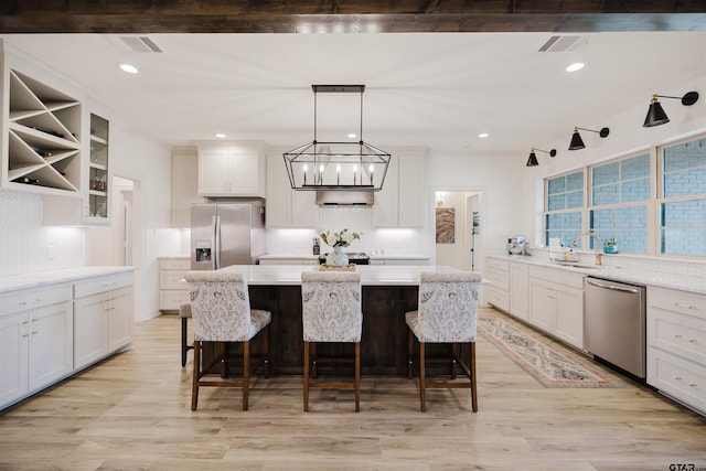 kitchen featuring visible vents, appliances with stainless steel finishes, a kitchen island, and light wood-type flooring