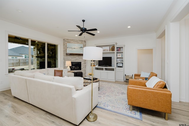 living area featuring light wood finished floors, a fireplace, recessed lighting, ceiling fan, and crown molding