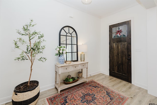 foyer with crown molding, light wood-style flooring, and baseboards