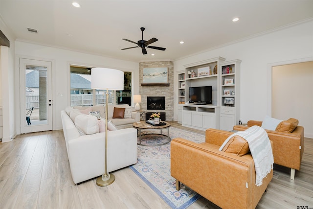 living room featuring visible vents, a fireplace, light wood-type flooring, and ornamental molding