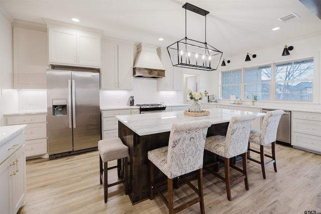 kitchen featuring custom range hood, light wood-type flooring, visible vents, and stainless steel appliances