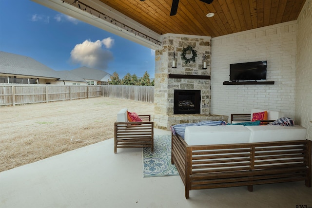 view of patio / terrace with an outdoor living space with a fireplace, a ceiling fan, and a fenced backyard