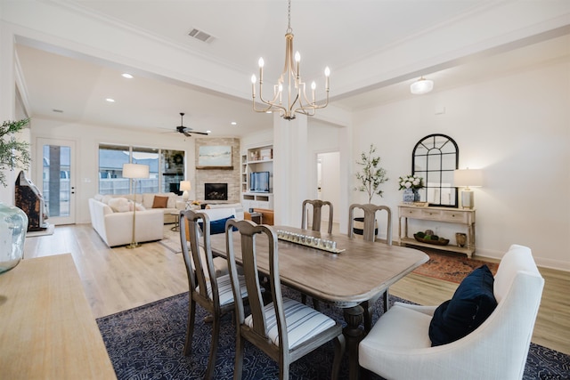 dining room with wood finished floors, visible vents, baseboards, a fireplace, and ceiling fan