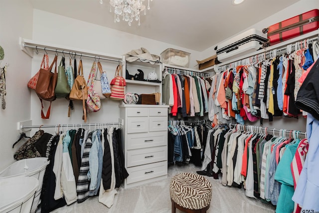 spacious closet with a chandelier and light colored carpet