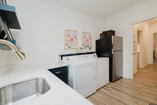 washroom featuring ornamental molding, a sink, light wood-style floors, laundry area, and washing machine and clothes dryer