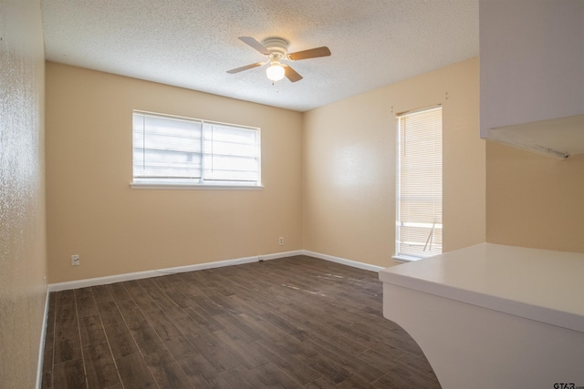 empty room with ceiling fan, dark wood-type flooring, and a textured ceiling