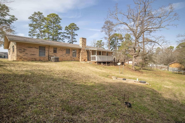 back of house featuring central AC unit and a lawn