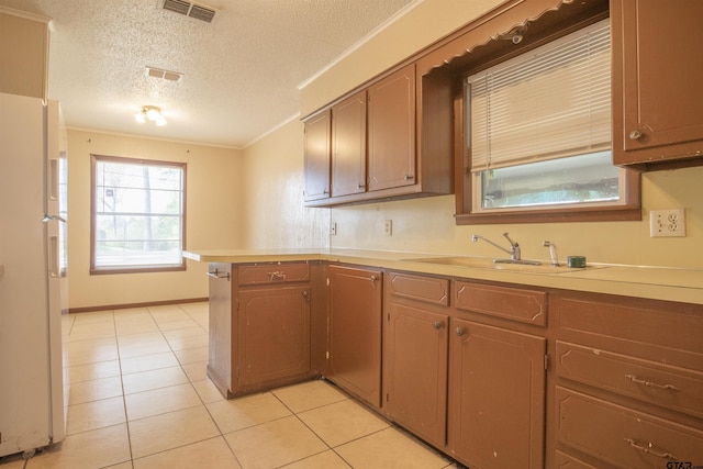 kitchen featuring sink, ornamental molding, white fridge, kitchen peninsula, and a textured ceiling