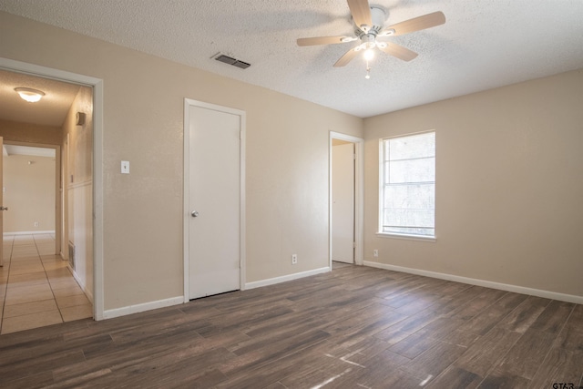 unfurnished bedroom featuring dark wood-type flooring, ceiling fan, a closet, and a textured ceiling